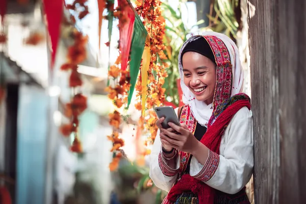 Cassino Móvel BB22 — Jogue a qualquer hora e em qualquer lugar Um jogador usando seu smartphone durante um evento festivo local, representando o cassino totalmente compatível com dispositivos móveis do BB22.